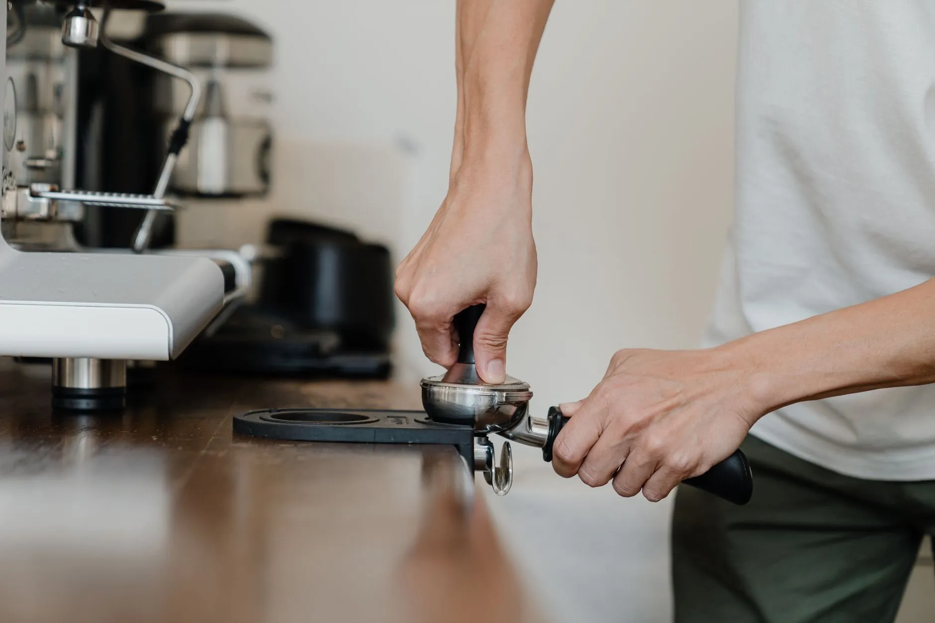A barista tamping espresso at the counter before the morning rush