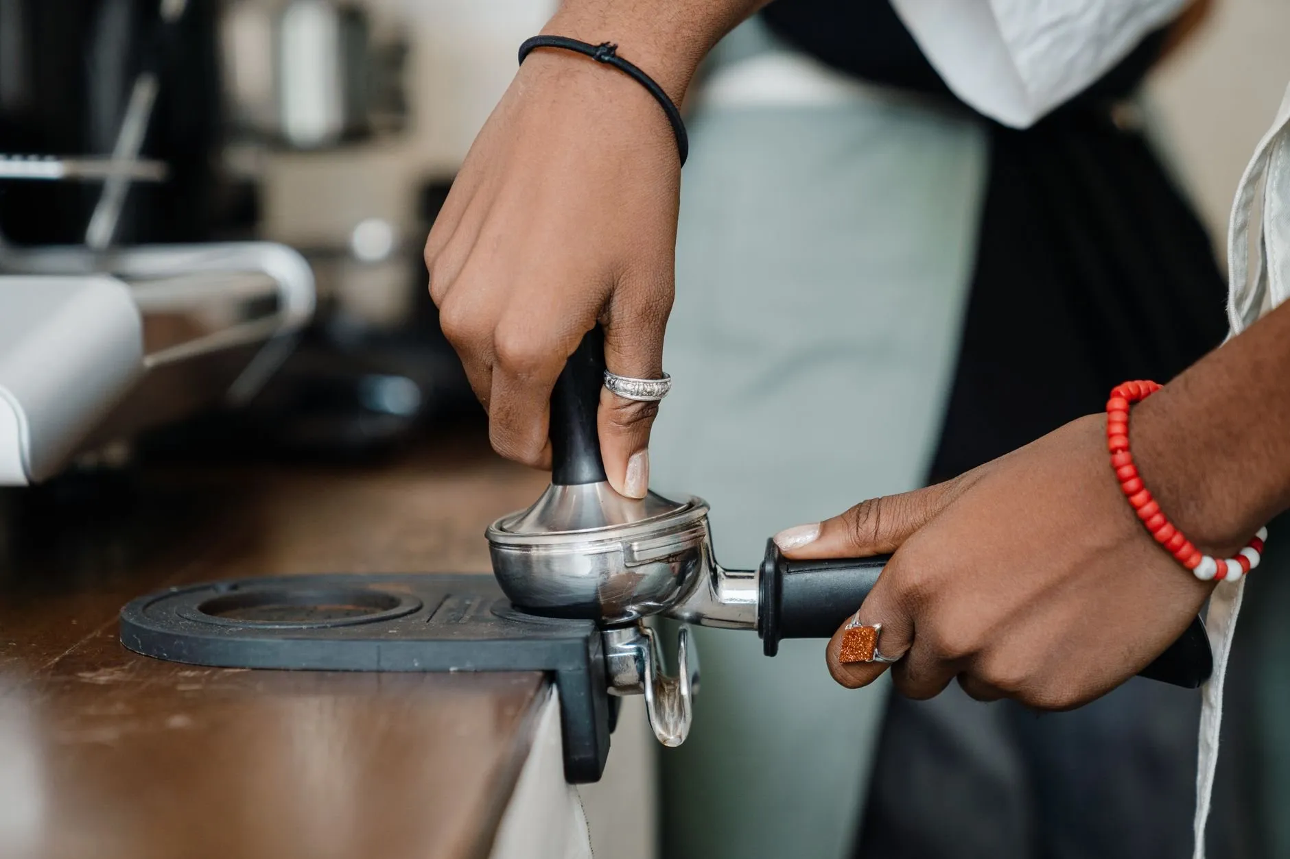 A barista tamping espresso into a portafilter on the counter
