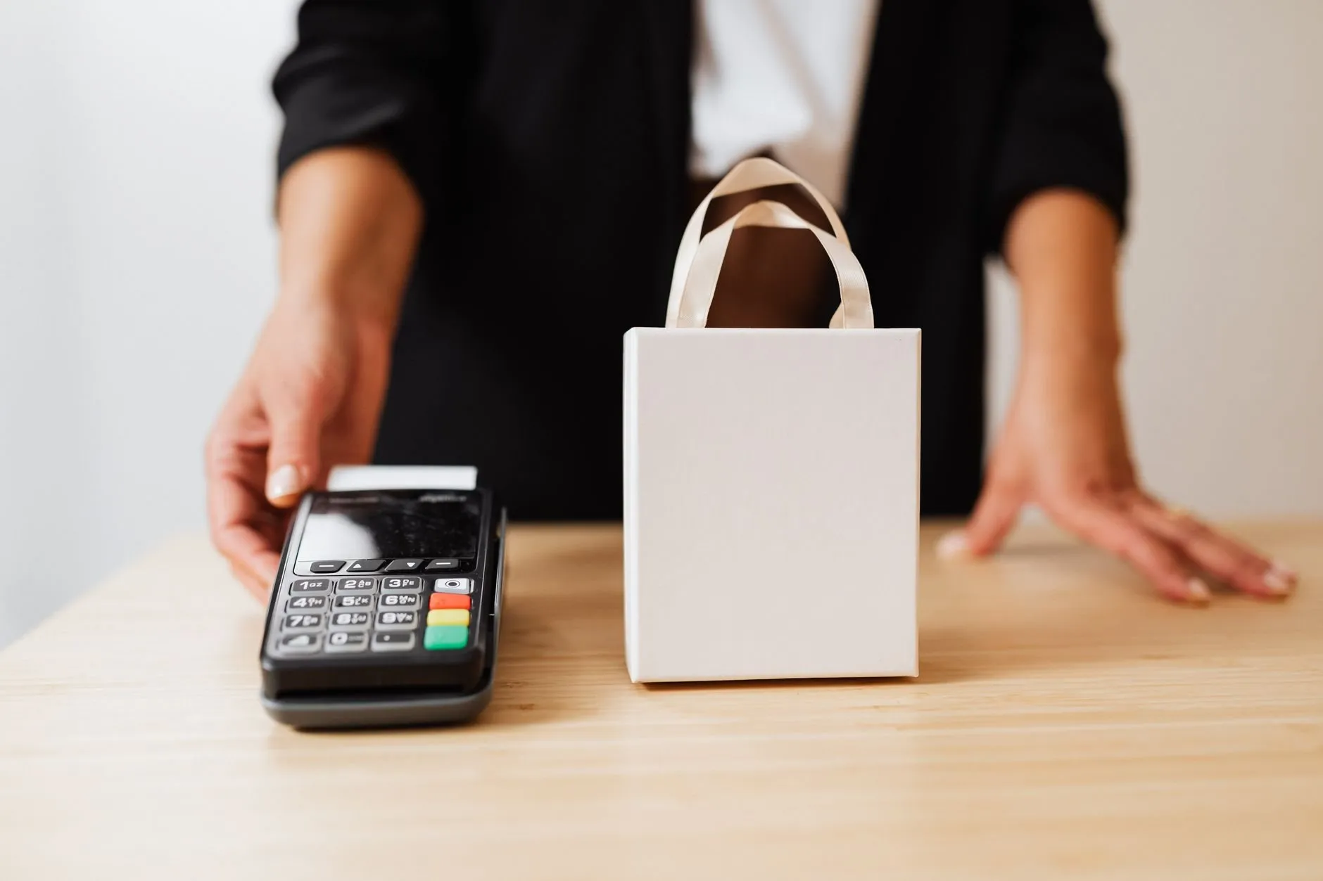 A shop assistant’s hand resting beside a card terminal on the counter